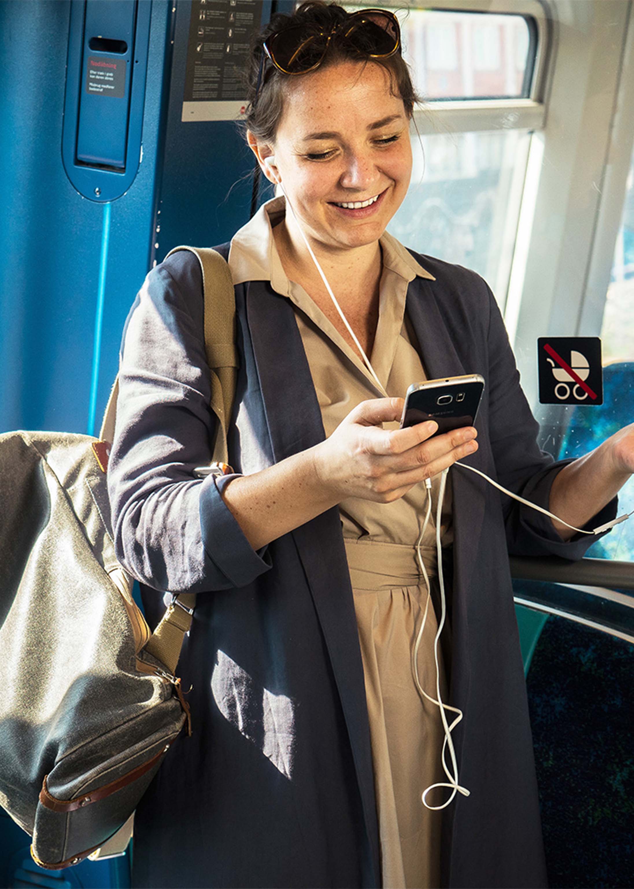 Nainen puhelimella junassa maksamassa lippua MobilePaylla.
