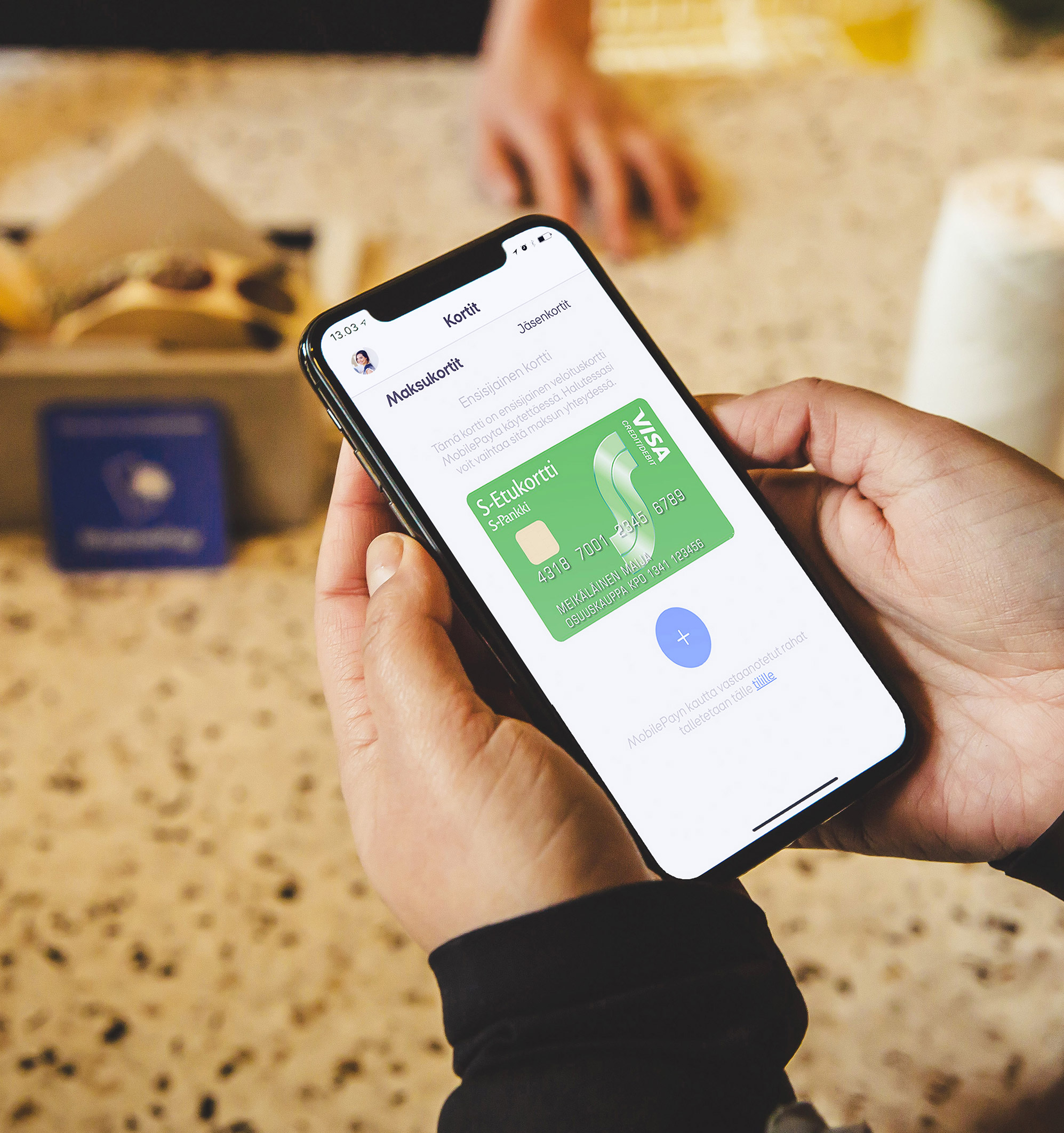 Ihminen kassalla tarkastelemassa lisättyjä kanta-asiakkuuksia MobilePay sovelluksessa