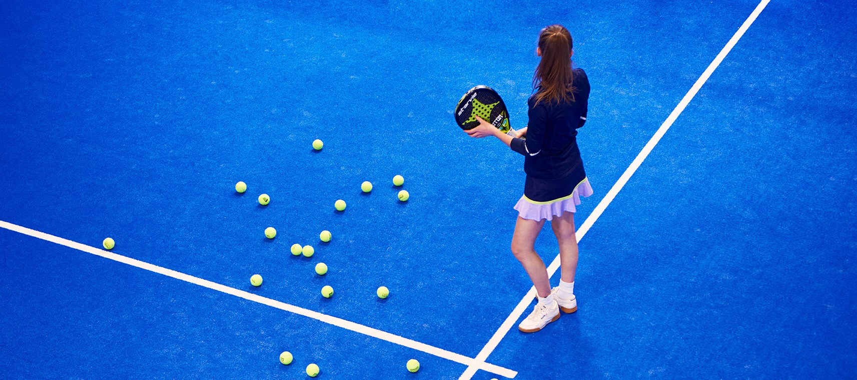 Tyttö sinisellä tenniskentällä