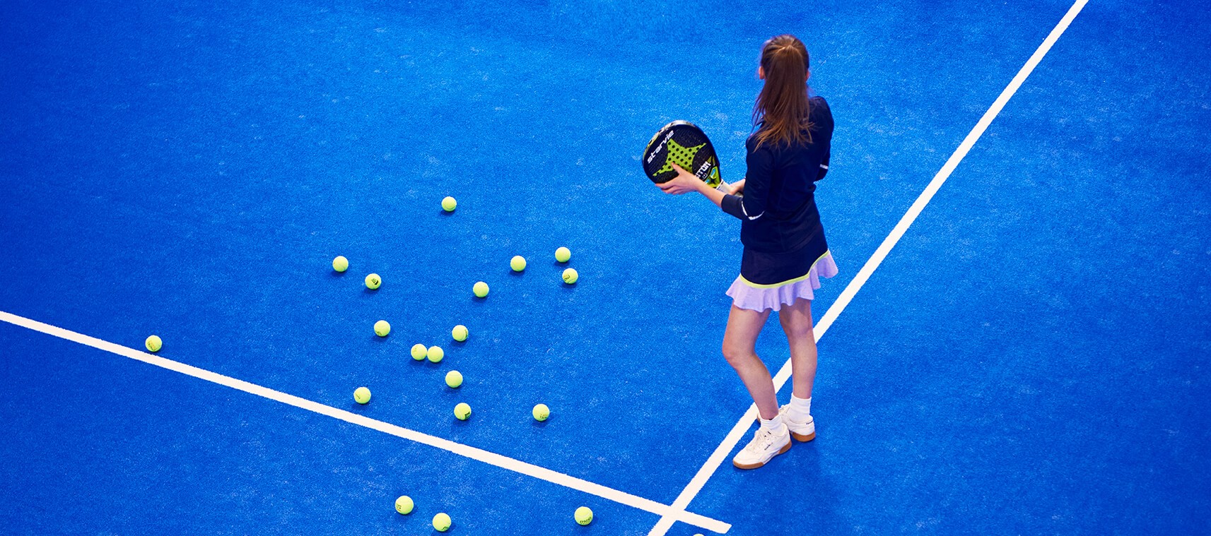 Tyttö sinisellä tenniskentällä